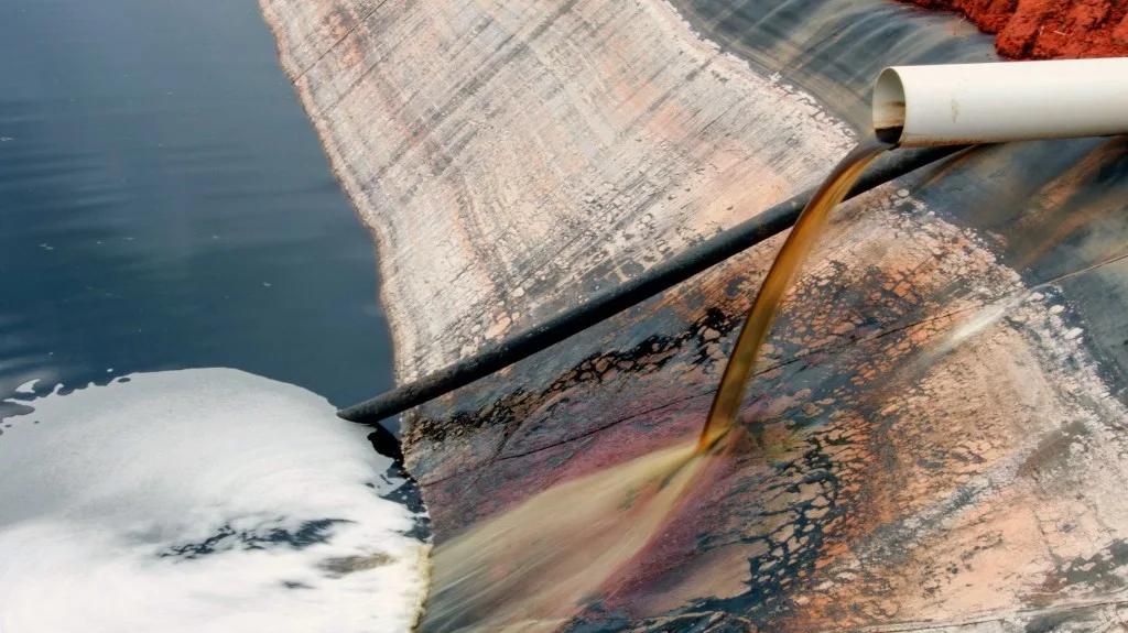 Leachate discharging from a pipe into a lined containment basin